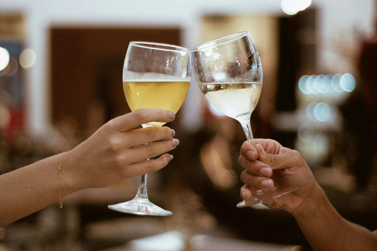Two people toasting wine glasses together to celebrate a new connection
